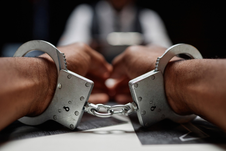 Dramatic close up of Black man wearing handcuffs on hands